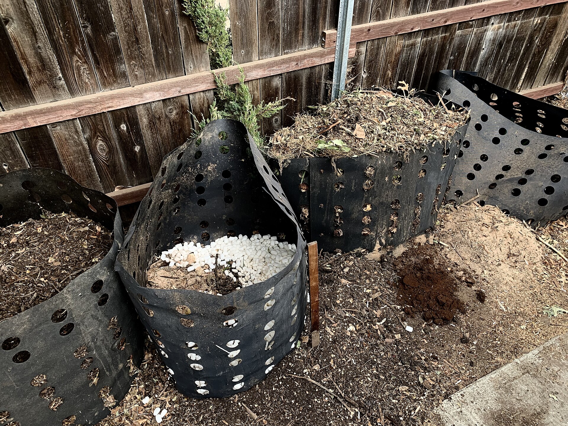 Compost bins with perforated liners in a backyard setup