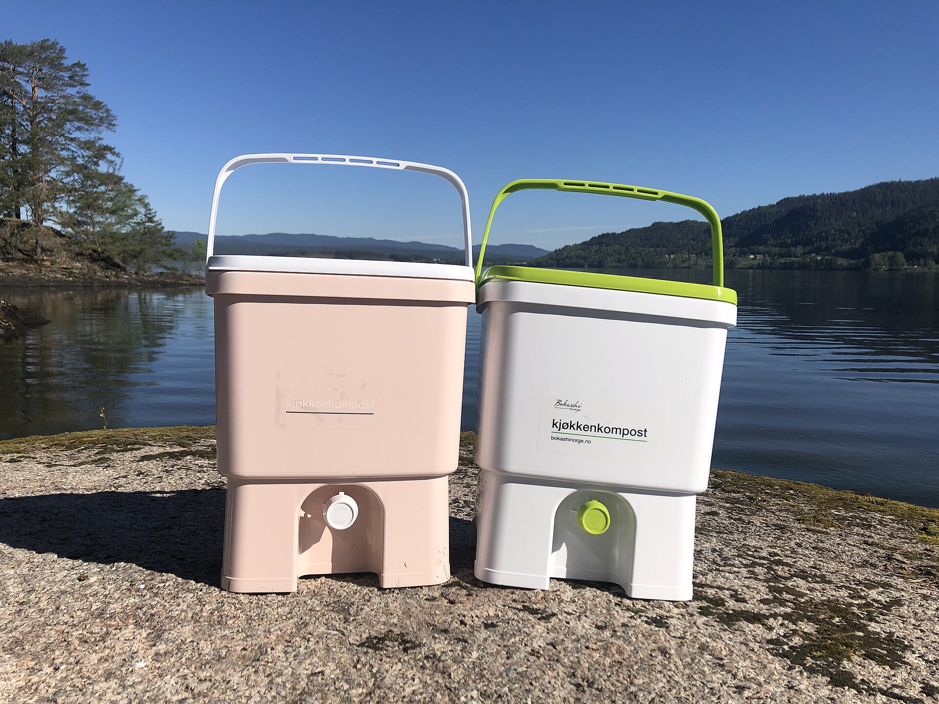 Two bokashi fermentation buckets on a lakeside garden path